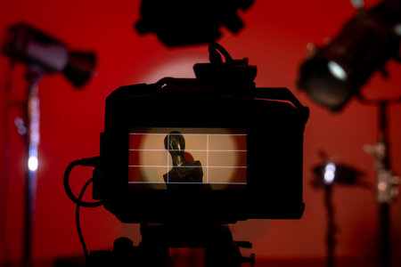 A close up of the camera viewfinder captures a mannequin and a colorful studio scene with dramatic lighting in shades of red color. Backstage photo shoot with professional lighting equipment.の写真素材