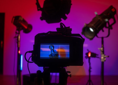 A close up of the camera viewfinder captures a mannequin and a colorful studio scene with dramatic...