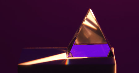 A close up of a glass pyramid with a gradient purple light, creating an abstract geometric aesthetic.の写真素材