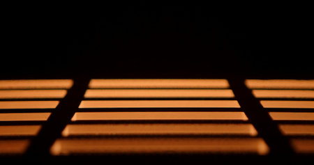 Minimalistic abstract image of warm orange light bars in darkness, creating a geometric striped...