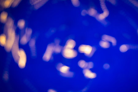 Artistic abstract background featuring soft golden bokeh against a deep blue background, creating a calming visual effect.の写真素材