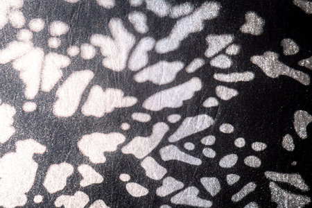 Closeup of abstract light spots projected onto dark textured surface, creating a high contrast...