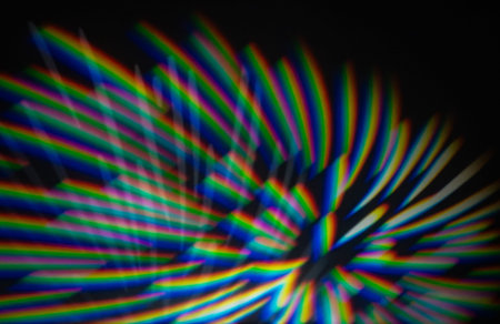 Colorful rainbow light stripes from a gobo projector create an abstract spectrum pattern on a dark...