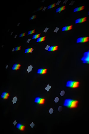 Abstract rainbow gobo projection with bright spectral streaks and soft star bokeh on a dark studio...