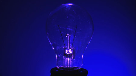 Close up of a light bulb against a deep blue background, symbolizing innovation and technology.の写真素材