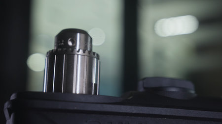 Detailed close up of a shiny metal mechanical component attached to a black device with blurred...