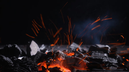 Hot charcoal embers at the bottom with orange sparks rising into dark copy space, perfect for fire, heat, barbecue, energy, and dramatic background design.の写真素材