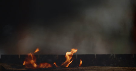 Minimal low key scene with small orange flames and drifting smoke, creating a moody background for...