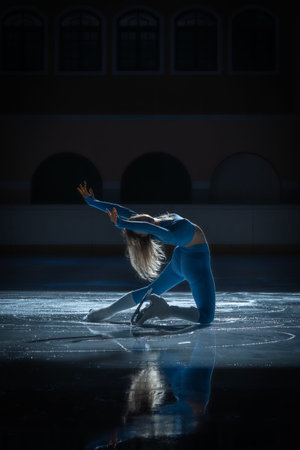 Female figure skater performance on indoor ice rink with bright sun flare, reflection and dramatic...