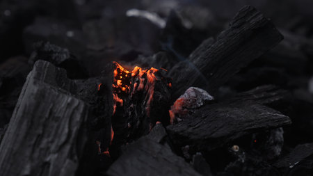 Moody close up of black charcoal with a glowing ember and ash texture, ideal for fire, heat, grilling, energy, and industrial background concepts.の写真素材