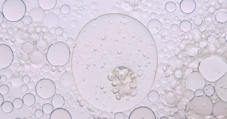 Soft abstract beauty background with delicate oil bubbles floating in clear liquid, illuminated by...