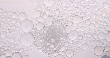 Soft abstract beauty background with delicate oil bubbles floating in clear liquid, illuminated by...