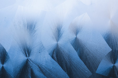 Close up view of intricate frosty patterns and snow on a glass surface, capturing the cold winter...