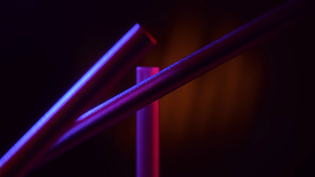 Minimalist magnetic pendulum desk sculpture illuminated with neon blue and pink light on a dark...