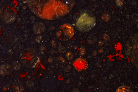 Abstract background of red paint and bubbles floating on dark divorces liquid surface, creating...