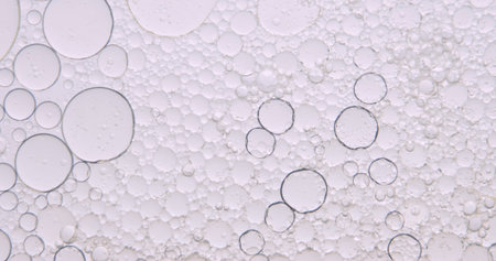 Soft abstract beauty background with delicate oil bubbles floating in clear liquid, illuminated by...