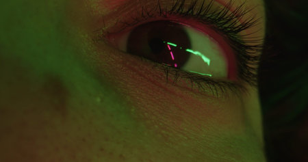 Macro shot up of a brown woman eye in green lighting. Concept of optics and vision, eye health, the...
