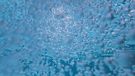 Abstract underwater view of turbulent air oxygen bubbles in a blue swimming pool. Concept of a spa,...