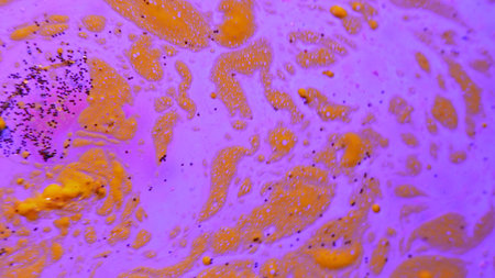 Abstract background of pink glitter scattered over purple liquid paint with yellow streaks. Concepts for modern art and creative design, chemical industry, education and science, fashion and textiles.の写真素材
