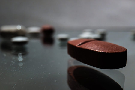 Macro tablet on a reflective surface with blurred medicine in the background. Concept of healthcare, pharmacy, medication, treatment, product branding and pharmaceutical advertising.の写真素材