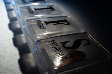 Weekly pill organizer with labeled daily compartments displayed in bright studio lighting. Concept...