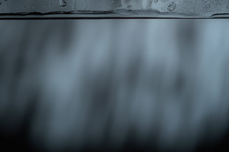 Moody dark abstract background with water droplets and streaks running down a glass surface, softly...