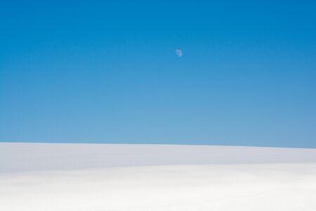 Snowy field and moon in the blue winter skyの写真素材