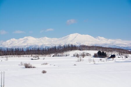 Snow field and mountains with a blue skyの写真素材