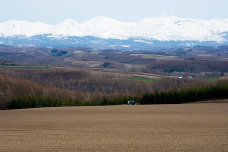 Spring field and mountains with remaining snow