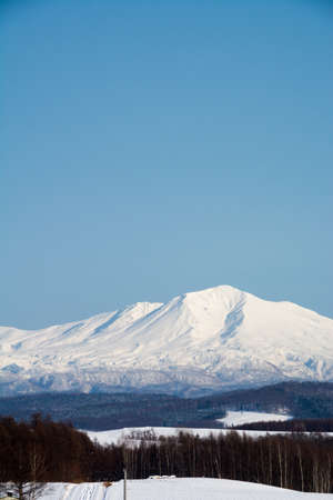 Winter hills and snowy summits with a blue skyの写真素材