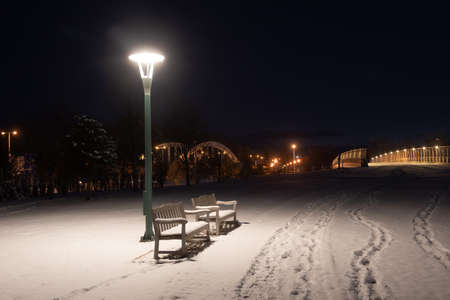 Park bench on a snowy winter's nightの写真素材