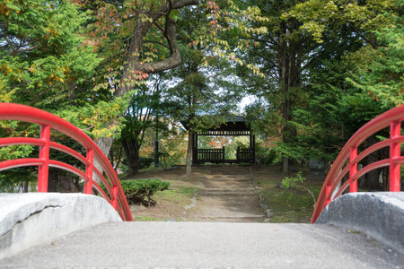Red arch bridge and pavilion in the parkの写真素材