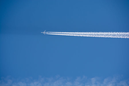 Airplane in the blue sky with a trail of white smoke.