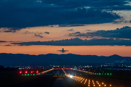 Airplane landing in the airport with colorful lights at sunset.