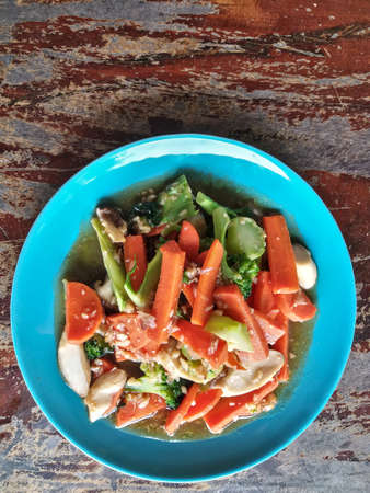 Healthy Asian Food Stir-fried Vegetables with Oyster Sauce on Blue Plate Natural Light on Wooden Table Vertical Top Viewの写真素材