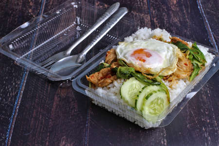 Stir-fried menu with curry paste, pork slices, fried egg with steamed rice, ready-to-eat food at peak times.の写真素材