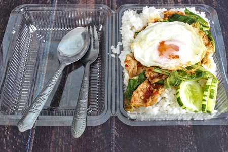 Stir-fried pork with curry paste, fried egg in a clear plastic box, ready-to-eat food at peak times of the day.の写真素材