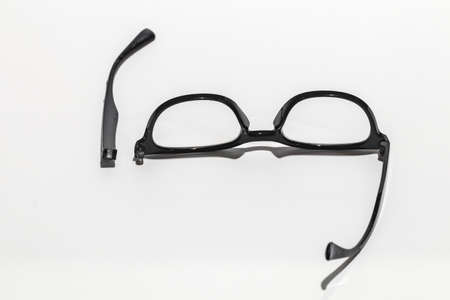 The glasses are damaged, the parts are separated. Focus on the legs of the glasses that have come off. Put on a white backgroundの写真素材