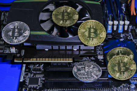 Bitcoin coins that are placed on a VGA card and a computer motherboard. Concept about Cryptocurrency Bitcoin Finance Investments and Stop Mining When Prices Dropの写真素材