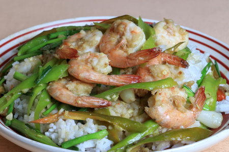 Stir-fried prawns with bell peppers and spring onions, topped over steamed rice, ready-to-eat fast food.の写真素材