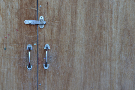 The front door is a large wooden board. with handle and metal hook
