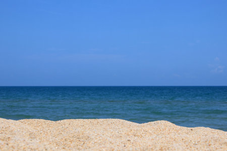 The foreground is a multi-level sand dune, overlooking the sea and bright blue sky.