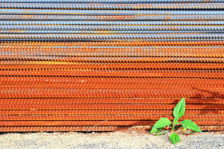 Steel bars for building structures are stacked in layers at construction sites, exposed to the sun and rain until they rust.の写真素材