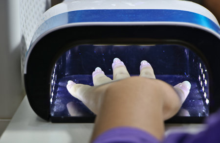 A female customer is using a nail dryer to dry her nails after applying nail polish.の写真素材