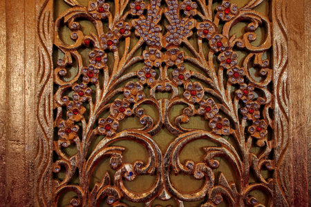 Elegant carved wooden panel featuring intricate floral patterns with gold finish and gem details,...