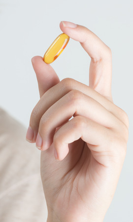 Closeup woman hand showing Fish oil capsules.の写真素材