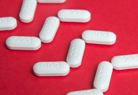 close up white pills  in row on red background.の写真素材