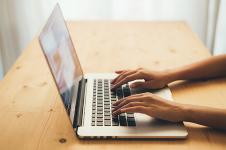 Woman hands typing on laptop keyboard at the office, Woman worker and business concept, Soft focus on vintage wooden table.の写真素材