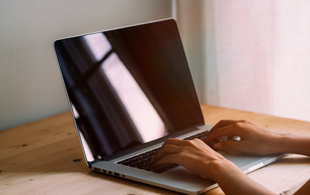 Woman hands typing on laptop keyboard at the office, Woman worker and business concept, Soft focus on vintage wooden table.の写真素材