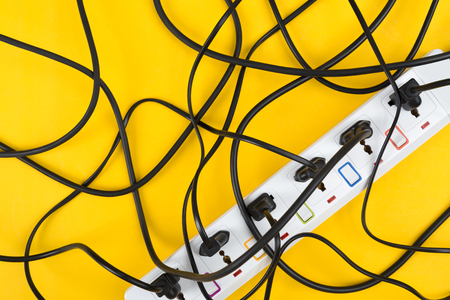 Maximum electrical cords connected electrical power strip or extension block  with messy wires, top view on colorful background, messy electric equipment flat lay concept.の写真素材